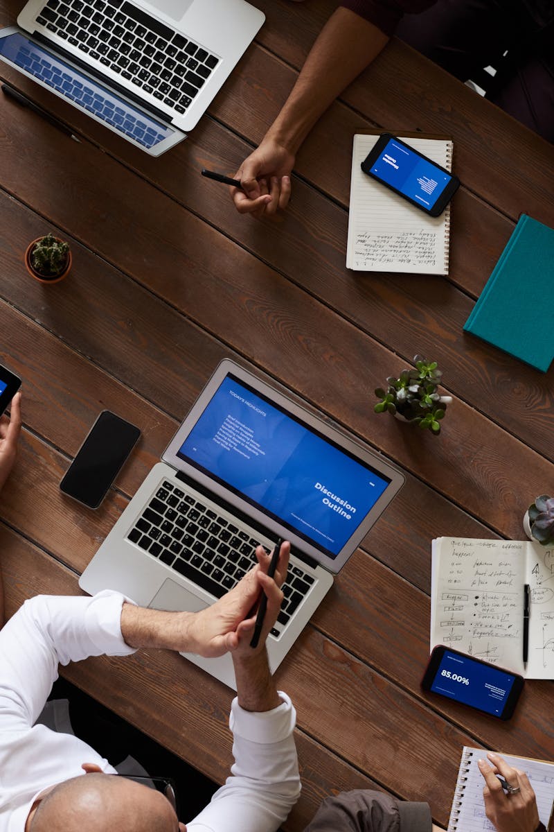 Home Overhead view of a diverse team discussing around a wooden table, using technology.