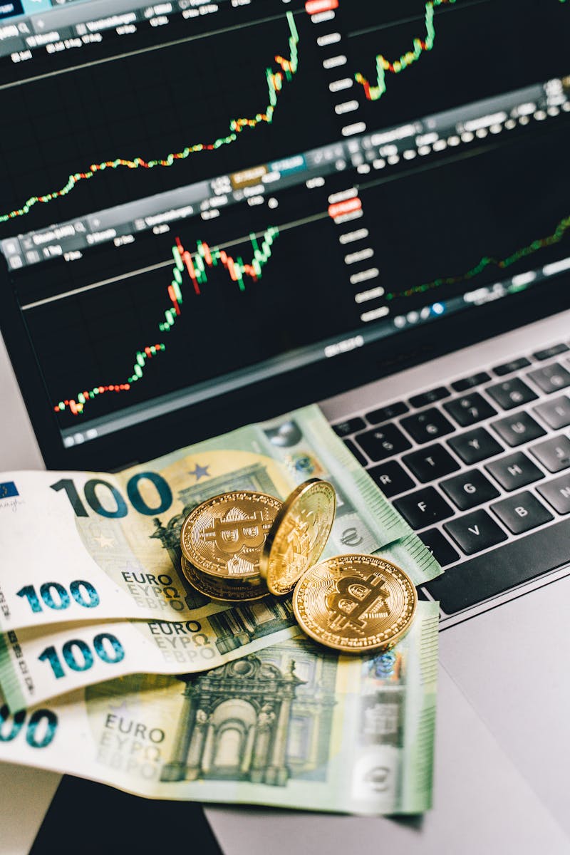 Home Bitcoin and Euro notes on laptop keyboard with stock market graphs in Berlin, Germany.